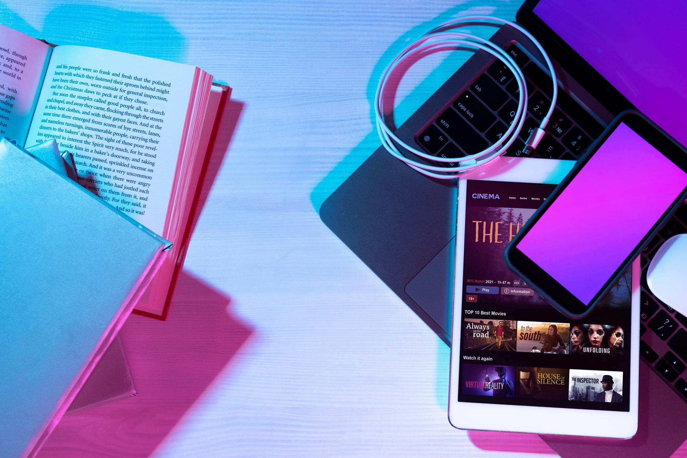 An open book beside a laptop and phone on a desk