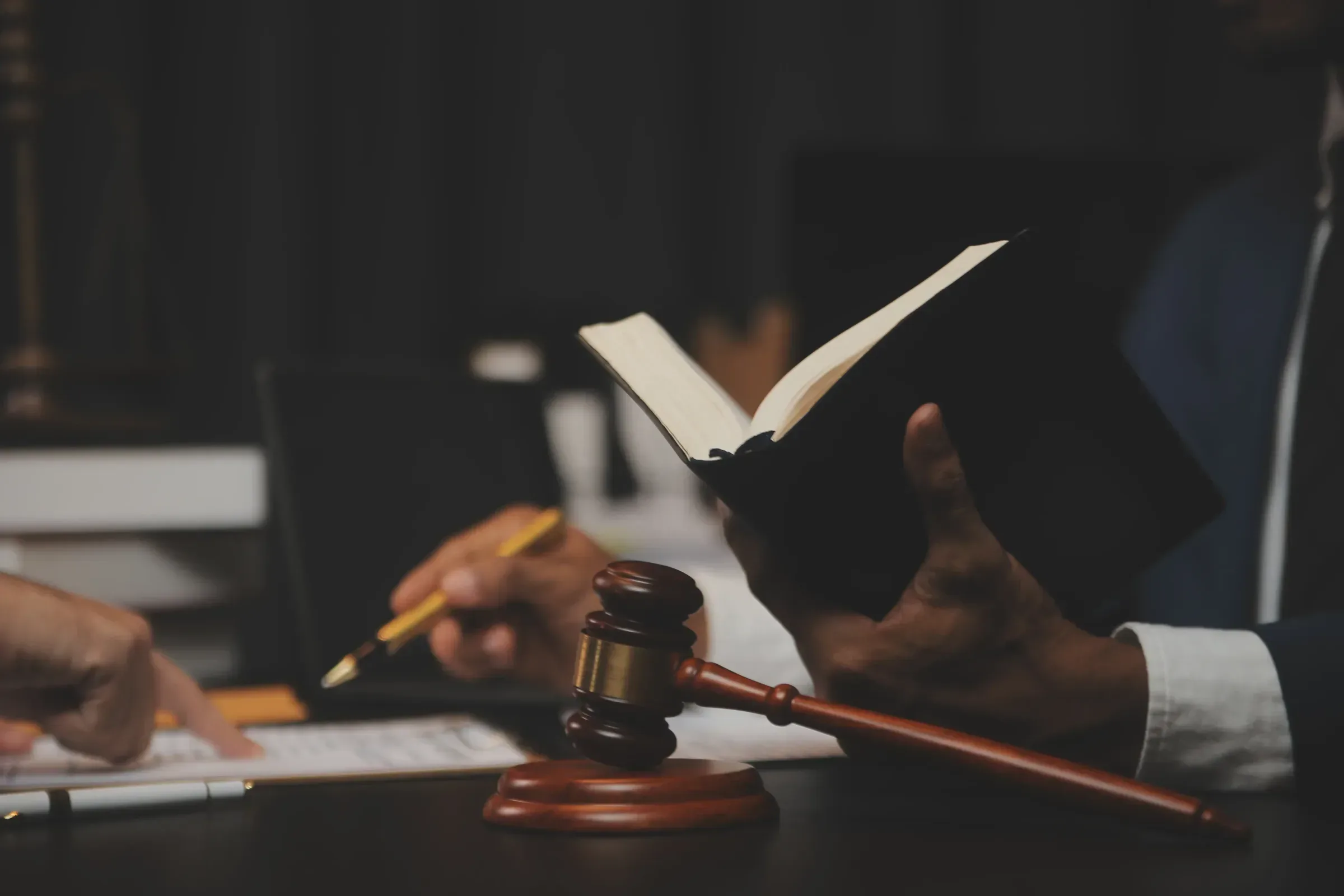 Lawyers reviewing a legal book beside a gavel at a desk